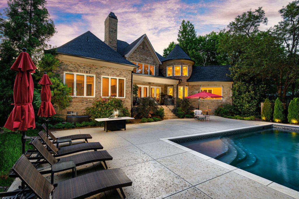 Twilight backyard pool and patio of a brick home with a turret