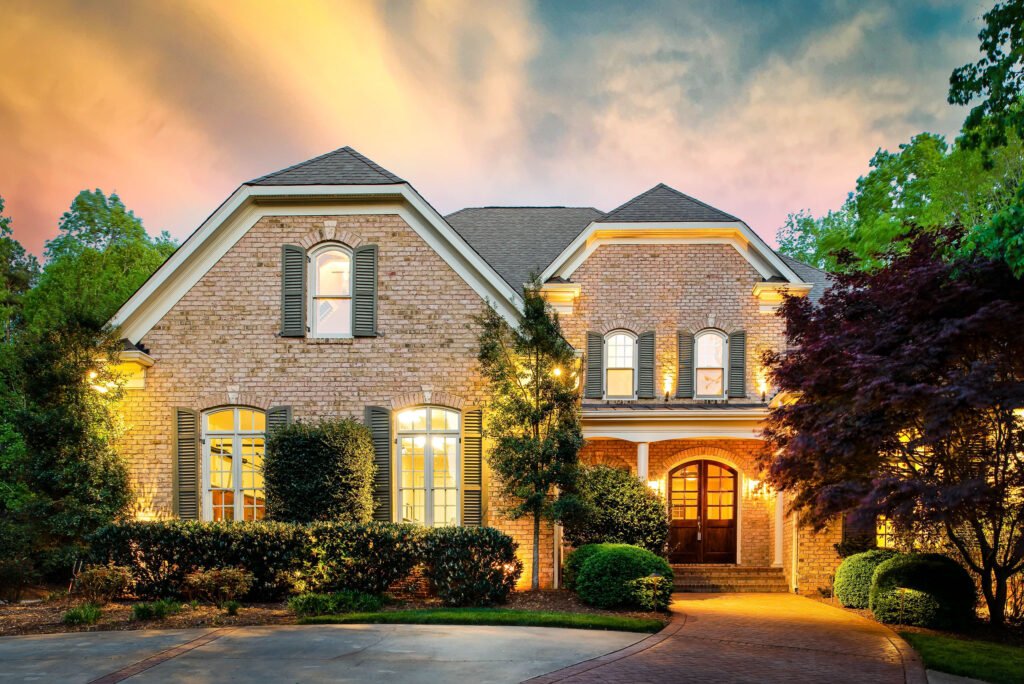 Brick home with an arched entry and circular drive at twilight