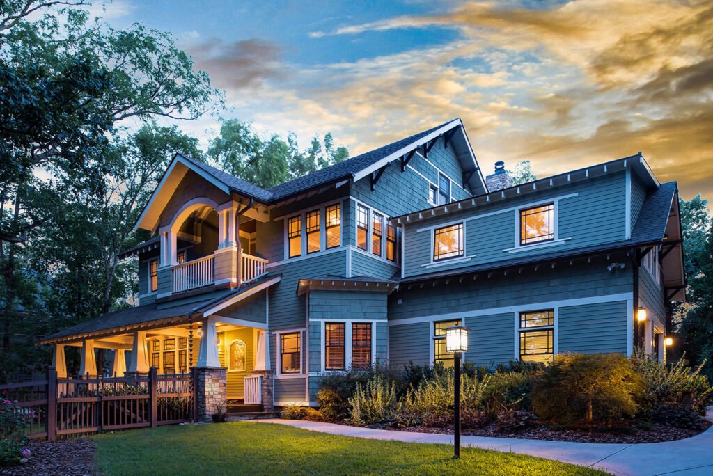 Blue-gray craftsman home at twilight with a lit front porch