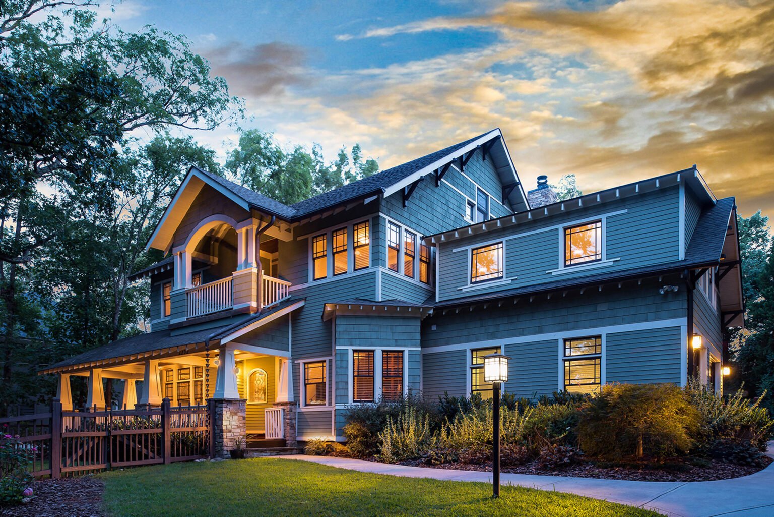 Blue-gray craftsman home at twilight with a lit front porch