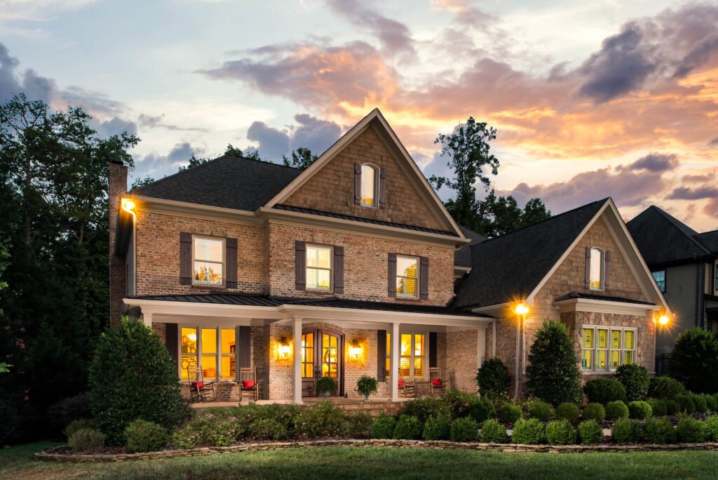 Craftsman brick home with a covered porch at twilight