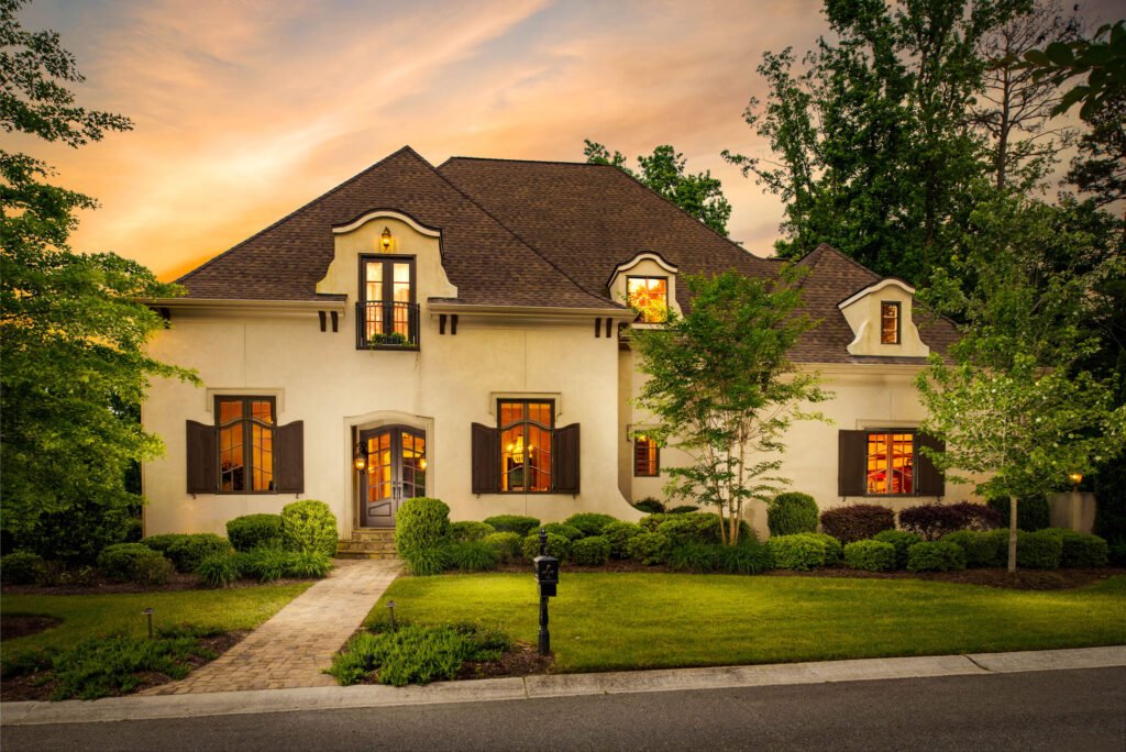 French provincial stucco home at twilight with glowing windows
