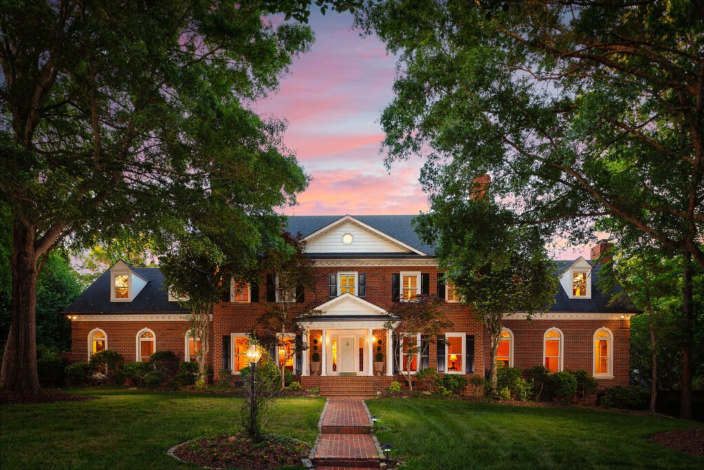 Georgian brick estate at twilight framed by mature trees